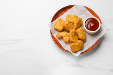 Delicious chicken nuggets and ketchup on white marble table, top view. Space for text