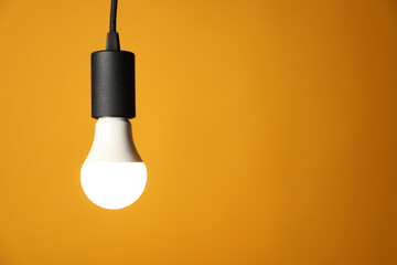 Light bulb against orange background, space for text