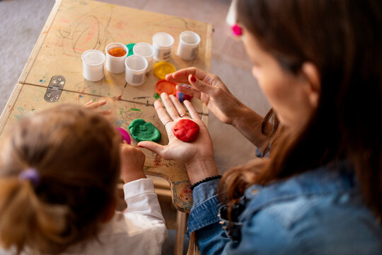 Mother showing her daughter how to play with modeling clay, developing her creativity and motor skills