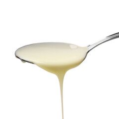 Delicious condensed milk pouring from spoon isolated on white