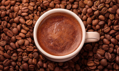 Fototapeta premium Mochaccino coffee cup on the table surrounded by roasted beans. Mocha mousse creative color of the year 2025 background in light brown shade with a mix of warm cacao tones