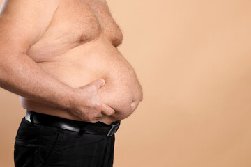 Naklejka premium Overweight problem. Man with excessive belly fat on beige background, closeup. Space for text