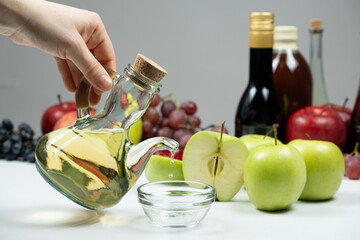 Apple cider vinegar pouring from vinegar bowl into glass sauce dish