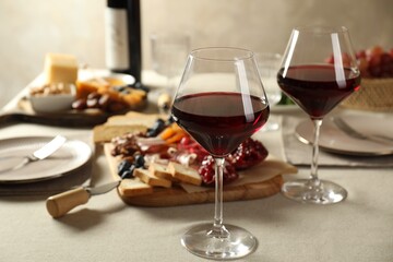 Red wine and different snacks served on light grey table