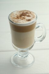 Tasty latte macchiato in glass cup on white wooden table, closeup