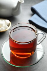 Refreshing black tea in cup on grey table, closeup