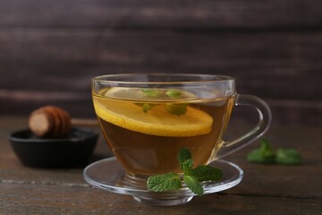 Tasty mint tea in cup, lemon and fresh leaves on wooden table, closeup