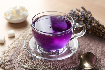 Aromatic lavender tea in glass cup and spoon on table, closeup