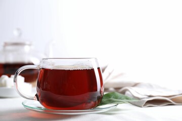 Refreshing black tea in cup on light table. Space for text