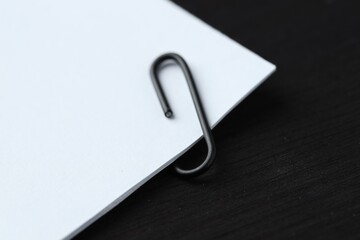 Paper notes with clip on black wooden table, closeup. Space for text