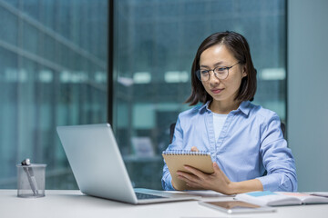 Serious and focused Asian woman listening to online webinar, remote business meeting conference....