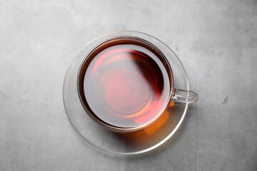 Aromatic black tea in cup on light grey table, top view