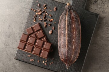 Cocoa pod and chocolate on grey table, top view