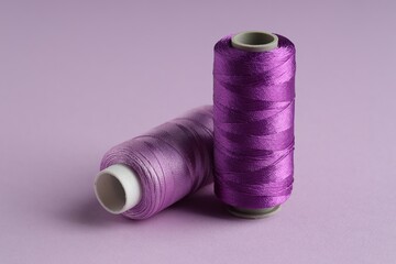 Spools of sewing threads on violet background, closeup