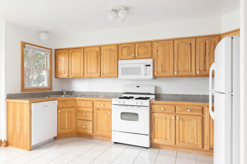 Bright kitchen with light wood cabinets, white appliances, square tile flooring, and granite countertops.  No brands or labels.