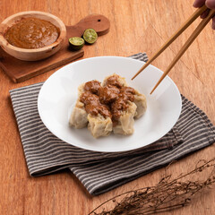 Steaming dumplings are beautifully arranged on a plate, drizzled with a rich sauce and accompanied by fresh lime for added flavor