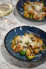 A close-up view of homemade gnocchi served on a blue plate, topped with freshly grated cheese