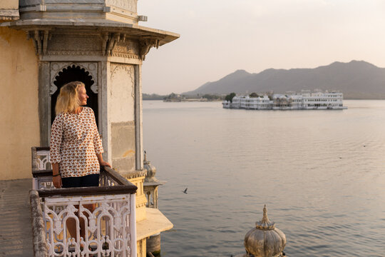 Young blonde woman watching sunset at the balcony of Udaipur city fort in Rajasthan, India