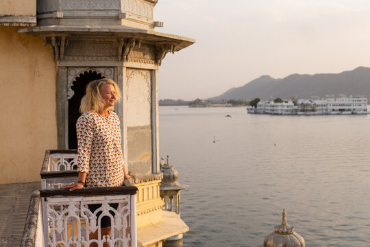Young blonde woman watching sunset at the balcony of Udaipur city fort in Rajasthan, India