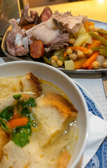 Traditional Portuguese chickpea stew (Cozido de Grão) with chickpeas, vegetables, potatoes, pork, and sausages, served in a rustic restaurant setting, capturing authentic culinary heritage.