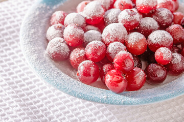 A saucer of cranberries sprinkled with powdered sugar, close-up