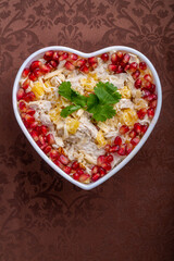 Chicken and pineapple salad decorated with pomegranates in a heart-shaped salad