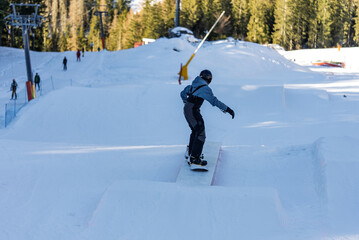 Children in snowpark in Dolomites Alps. Snow park box tricks. Snowboarder in park on a box. Winter...
