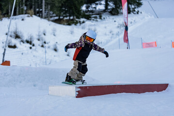 Children in snowpark in Dolomites Alps. Snow park box tricks. Snowboarder in park on a box. Winter...