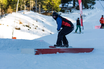 Children in snowpark in Dolomites Alps. Snow park box tricks. Snowboarder in park on a box. Winter...