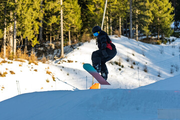Children in snowpark in Dolomites Alps. Snow park box tricks. Snowboarder in park on a box. Winter...