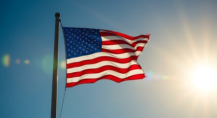 Obraz premium Proud American national flag waving gracefully against a clear blue sky with a bright sun flare, concept for patriotism, national holidays and political campaigns
