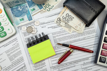 revenues from income tax form PIT-11 with pln zloty money with pen on office table.