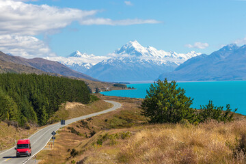 Campervan on Road to Mount Cook National Park over picturesque Lake Pukaki and Southern Alps, New Zealand