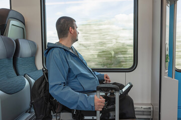 Male traveler with disability enjoying vacation and Europe train journey, sitting in a wheelchair...