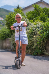 Adult woman wearing shorts and a t-shirt riding a scooter in the summer
