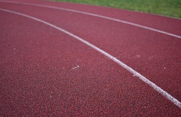 Fototapeta premium Red running track curve with green grass in right side.