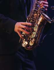 Fototapeta premium Concert view of saxophonist musician, saxophone sax player with vocalist and musical band during jazz orchestra show performing music on a stage in the scene lights, concert in a musical club hall