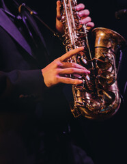 Concert view of saxophonist musician, saxophone sax player with vocalist and musical band during jazz orchestra show performing music on a stage in the scene lights, concert in a musical club hall