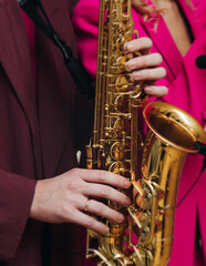 Obraz premium Concert view of saxophonist musician, saxophone sax player with vocalist and musical band during jazz orchestra show performing music on a stage in the scene lights, concert in a musical club hall