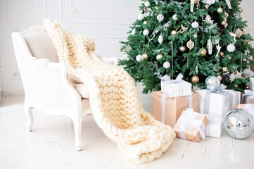 Elegant Christmas interior with a decorated tree in gold and white, wrapped gifts, a vintage beige...