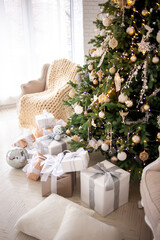 Elegant Christmas interior with a decorated tree in gold and white, wrapped gifts, a vintage beige sofa, and an armchair with a cozy knit blanket. Bright white walls create a festive, minimalism