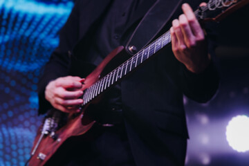Concert view of an electric guitar player with vocalist and rock band performing in a club, male...