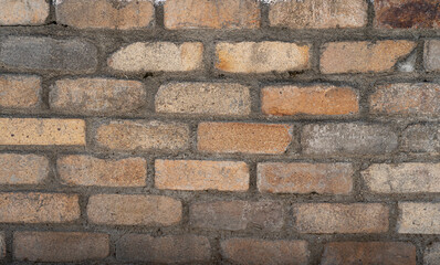 Fotografía Detallada de Pared de Ladrillos Antiguos en Tonos Beige y Marrón Claro, con Cemento Gris Irregular y Signos de Desgaste Natural en Exterior