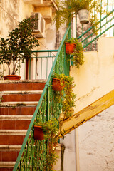 A classic Apulian balcony, staircasse draped in colorful flowers and potted plants, graces a...