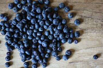 Fresh bilberries spread on wooden table top view. A lot of blue berries dropped on wooden table.