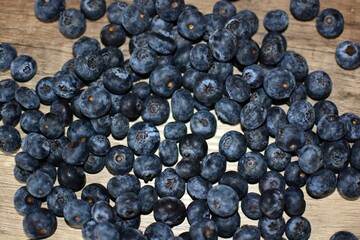 Fresh bilberries spread on wooden table top view. A lot of blue berries dropped on wooden table.