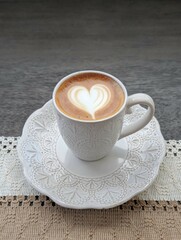 Elegant Cup of Coffee with Heart Latte Art on Ornate Ceramic Plate in Rustic Farmhouse Setting