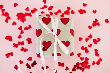 Happy valentines day. Stylish gift box with red hearts and pink bow on pink background flat lay. Love background