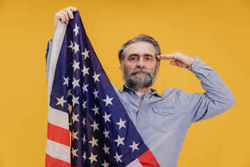 Patriotic senior man saluting while holding United States flag