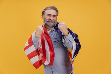 Proud Senior Man Celebrating with American Flag on Yellow Background